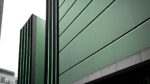 openart-tall-modern-building-facade-image-seen-from-sidewalk-in-green-and-grey-tones-general-tone-of-image-is-dark_nr0-vPzs_upscaled